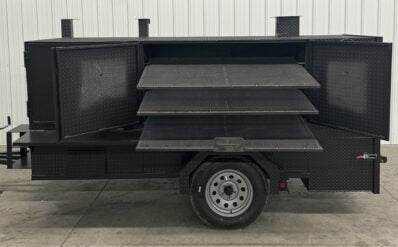 SNS 4060 smoker with cabinet main chamber and full storage featuring three slide-out cooking racks and built on a trailer for versatile catering use
