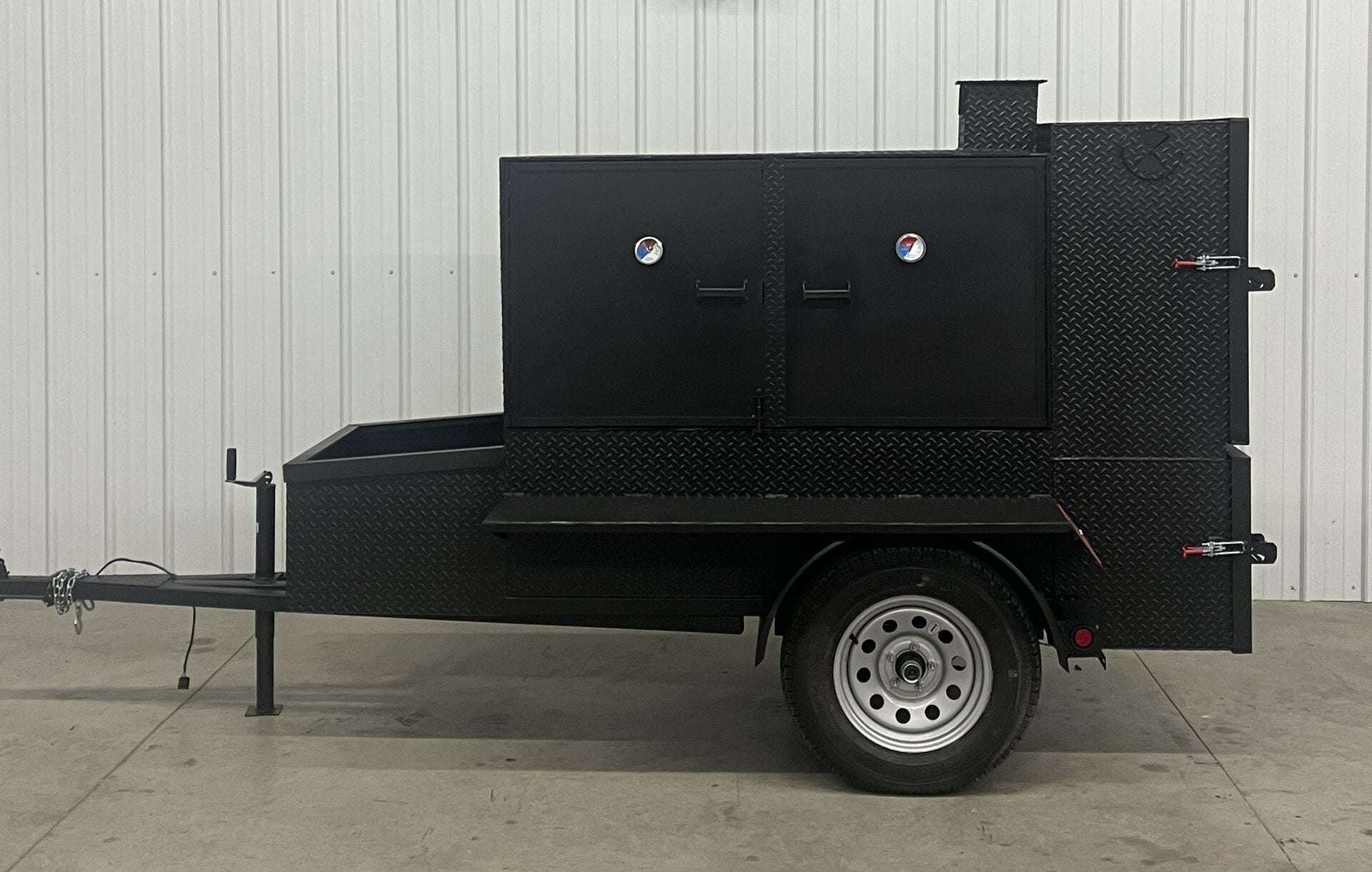 SNS 60 Cabinet trailer smoker made of 1/4 inch diamond tread steel with insulated firebox and three slide-out cooking racks.