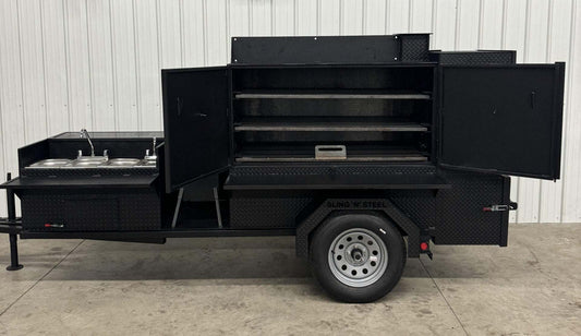 SNS 60 black steel smoker cabinet with sink, deep fryer, and multiple cooking racks on trailer.